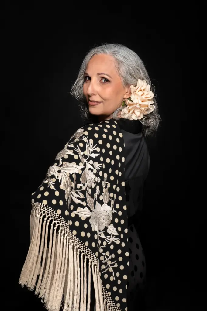 Rocío Pozo con mantón de manila negro de lunares y una flor blanca en el pelo