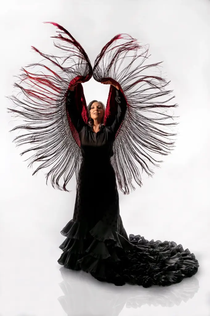 Rocío Pozo con el mantón desplegado en abanico rojo y negro, en composición simétrica